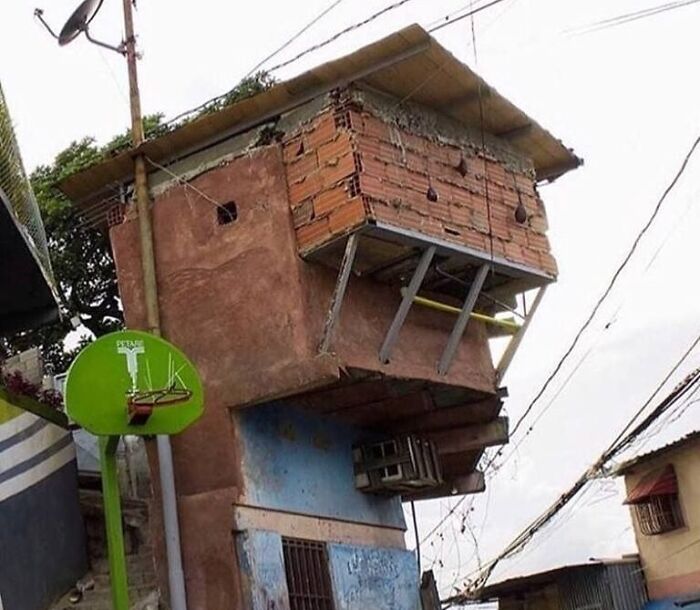 Leaning brick structure with precarious support beams and exposed wires showcasing architecture fails.