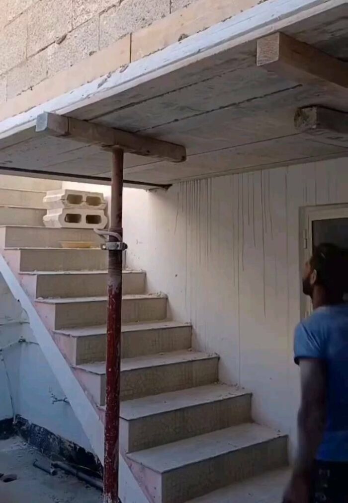 A man stands near stairs abruptly ending at a low ceiling in an architecture fail.