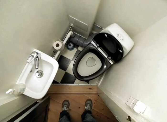 Cramped bathroom with awkwardly placed toilet and sink, showcasing an architecture fail.