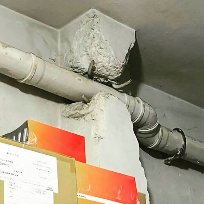 C*****d wall surrounds a misaligned pipe, illustrating an architecture fail.