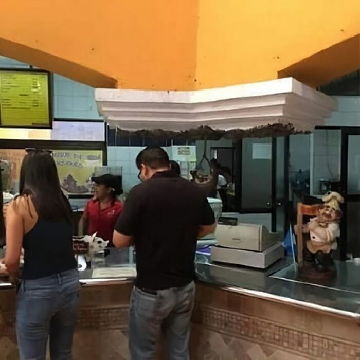 People standing under a protruding ceiling piece, showcasing an architecture fail at a restaurant counter.