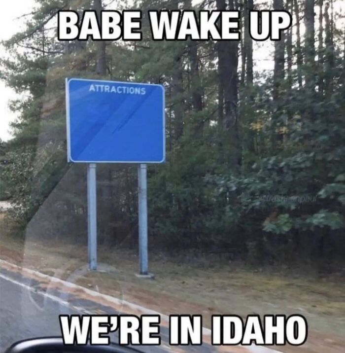 Road sign in Idaho humorously labeled "Attractions," surrounded by trees, referencing memes about the United States.