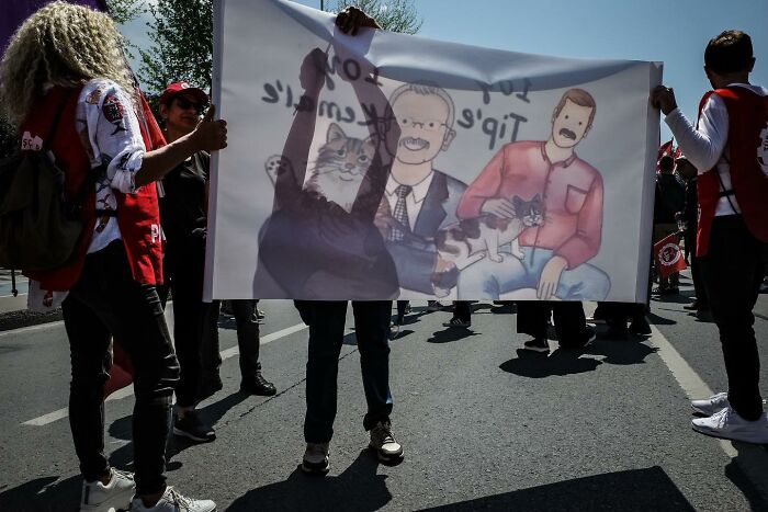 Street art banner held by people at a protest, showcasing Gökhan Arer's unique perspective.