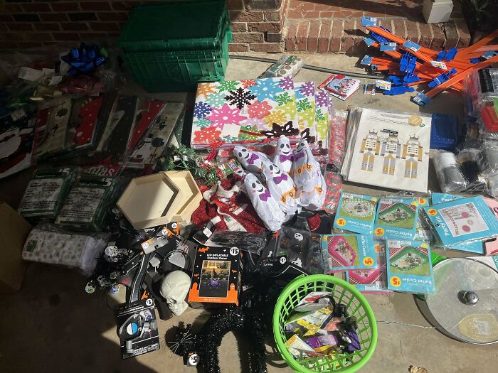 Dumpster diving treasures including holiday decorations and household items scattered on a floor in a dimly lit area.