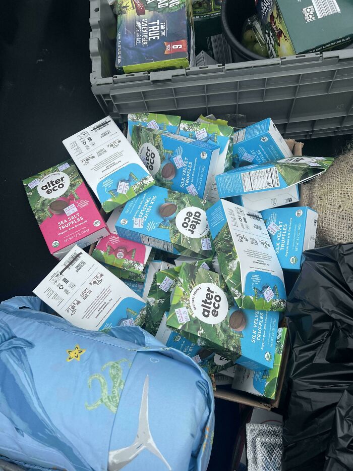 Pile of discarded Alter Eco truffles and other items found during dumpster diving treasures near a neighborhood.