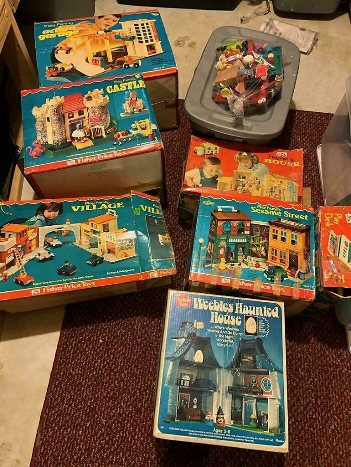 Vintage toys in original packaging, featuring classic sets like a castle and haunted house on a carpeted floor.