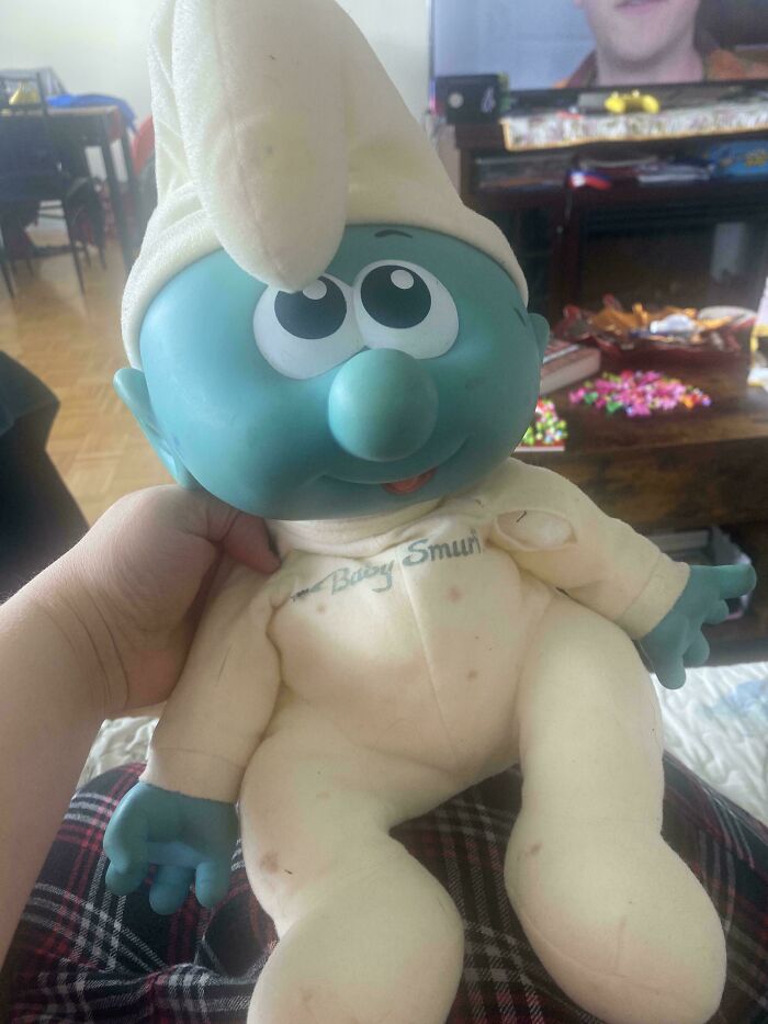 Vintage toy Smurf doll in a cozy room, held in hand, evoking childhood memories.