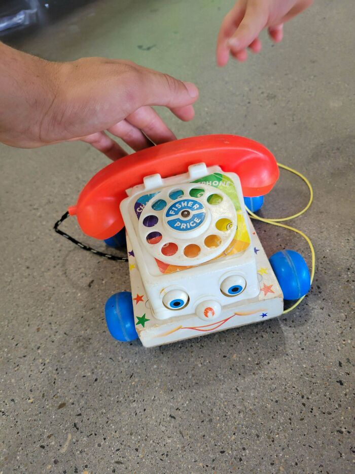 Vintage toy telephone with colorful dials and a smiling face on the floor.