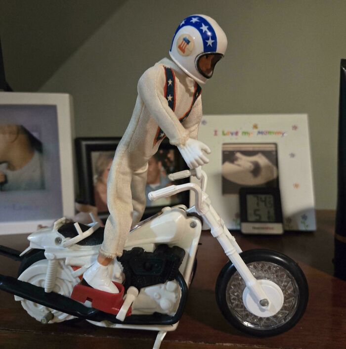 Vintage toy action figure on a white motorcycle with star helmet, displayed on a wooden table.