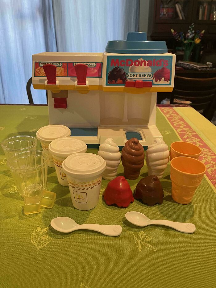 Vintage toy McDonald's soft serve set with cups, cones, and ice cream on a table, evoking childhood memories.