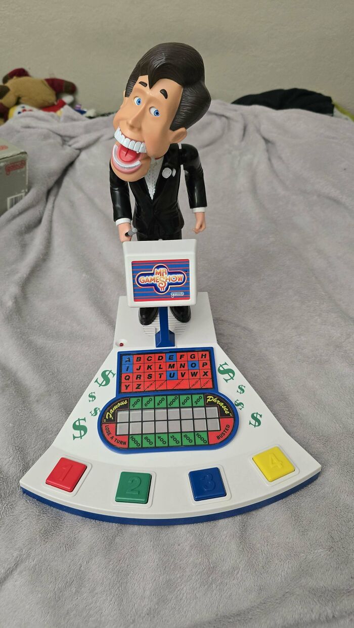 Vintage toy game show figure on colorful base with buttons and display.