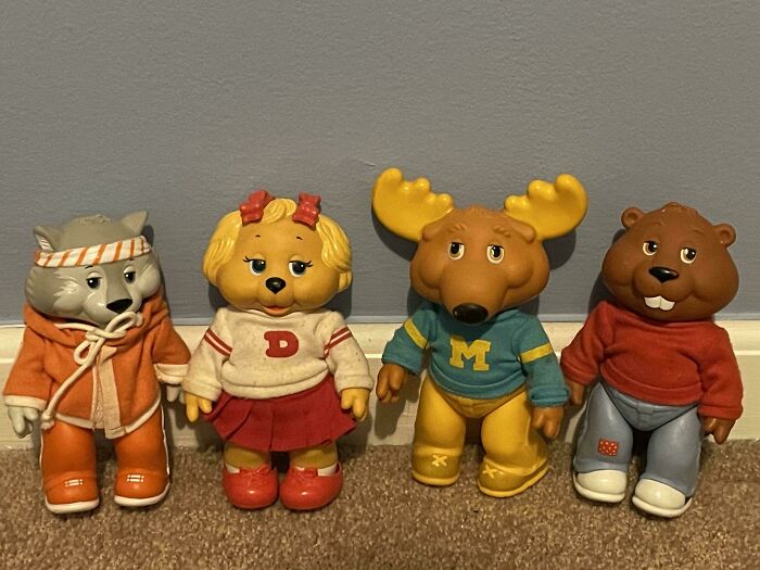 Vintage toys featuring animal characters in colorful outfits on a carpeted floor.