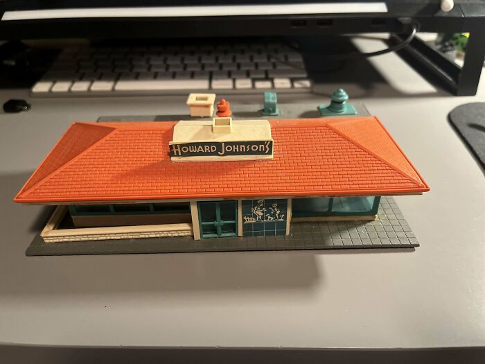 Vintage toy model of a Howard Johnson's restaurant with an orange roof on a desk.