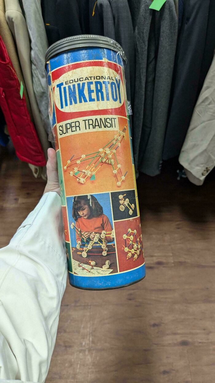 Hand holding a vintage Tinkertoy canister, featuring colorful construction set images.