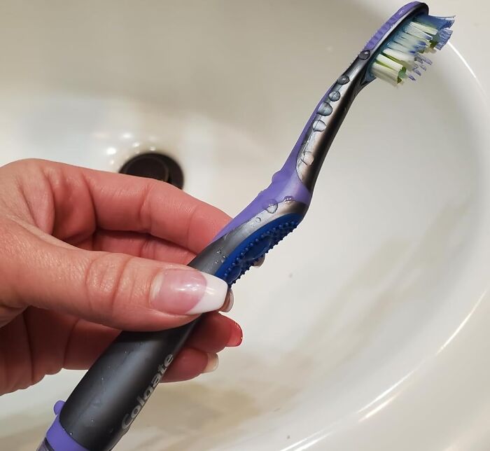 Hand holding a toothbrush over a sink, demonstrating an old school beauty hack.