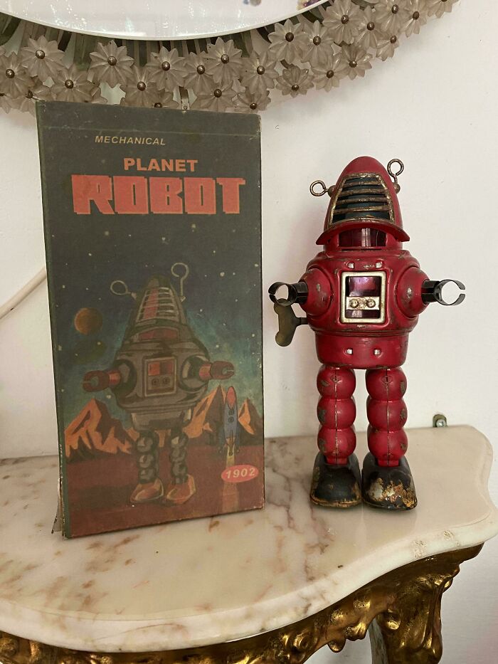 Vintage toy robot with original box, displayed on a decorative table, evoking childhood memories.