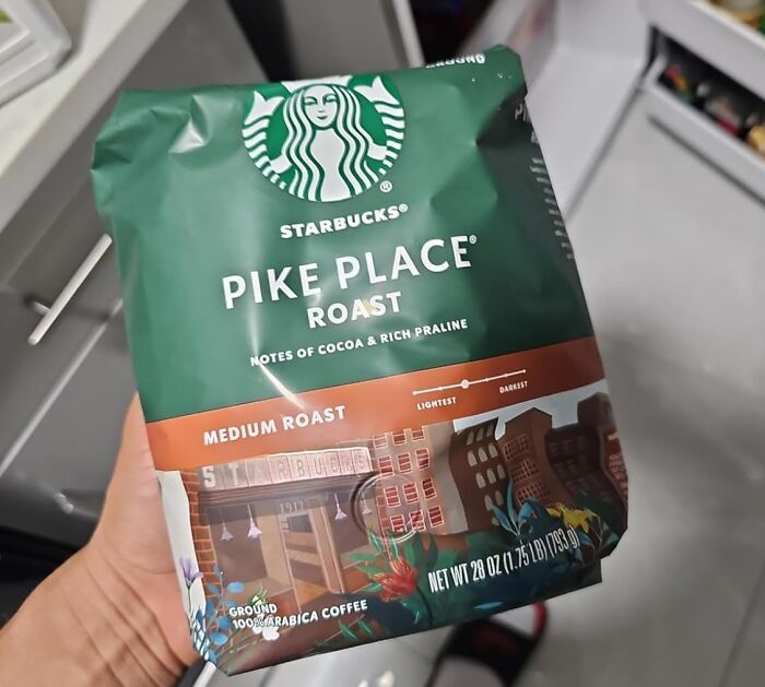 A hand holding a bag of Starbucks Pike Place Roast coffee, showcasing its medium roast label.