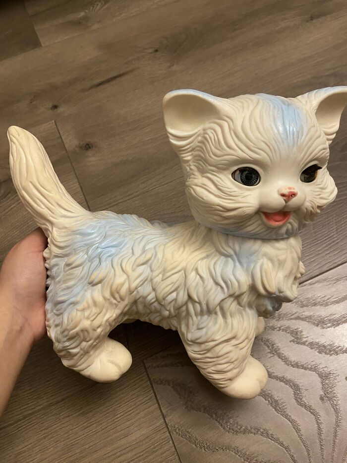 Vintage toy cat figurine held in hand, showcasing textured fur and playful expression.
