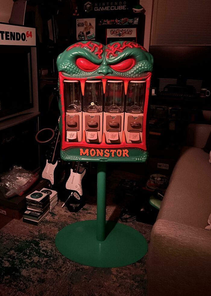 Vintage toy candy dispenser with monster face, surrounded by retro gaming items like Nintendo and GameCube.