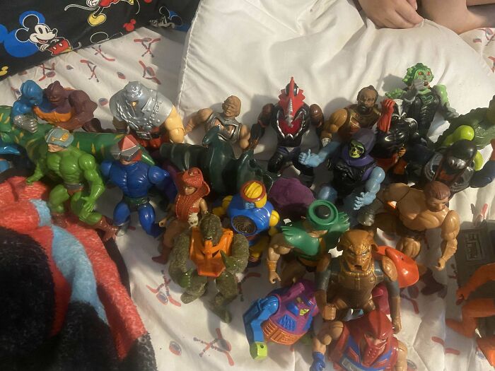 Vintage toys including action figures arranged on a bed, evoking childhood nostalgia.