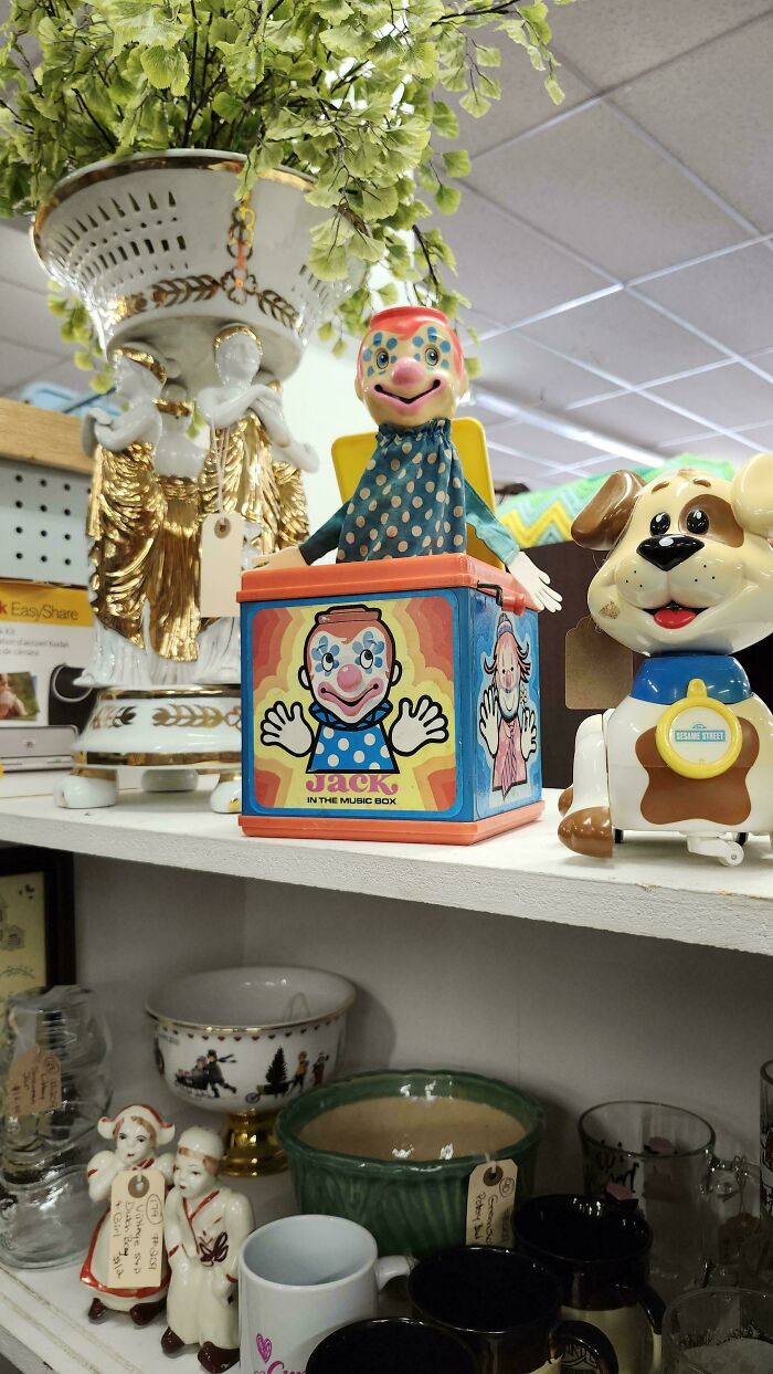 Vintage toys on a shelf, including a Jack-in-the-box clown and a toy dog, evoke nostalgic childhood memories.