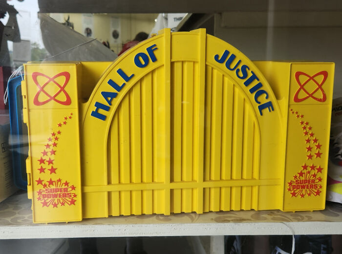 Yellow vintage Hall of Justice toy with blue lettering and red star graphics.