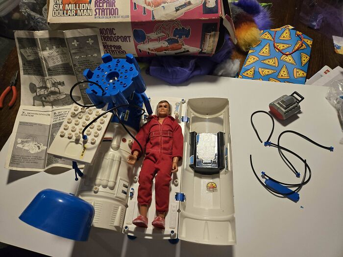 Vintage toys display featuring a Six Million Dollar Man action figure with accessories and original packaging.