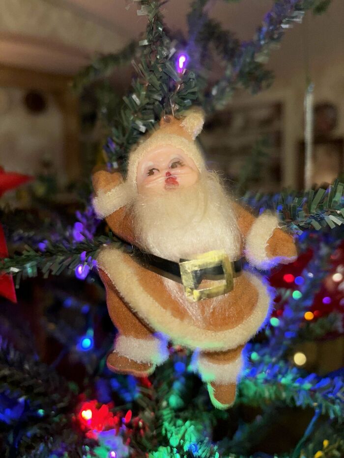 Vintage Santa Claus toy ornament on a Christmas tree with colorful lights.