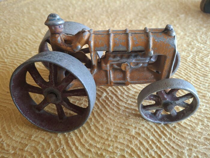 Vintage toy tractor with a rustic finish and detailed wheels, reminiscent of childhood nostalgia.