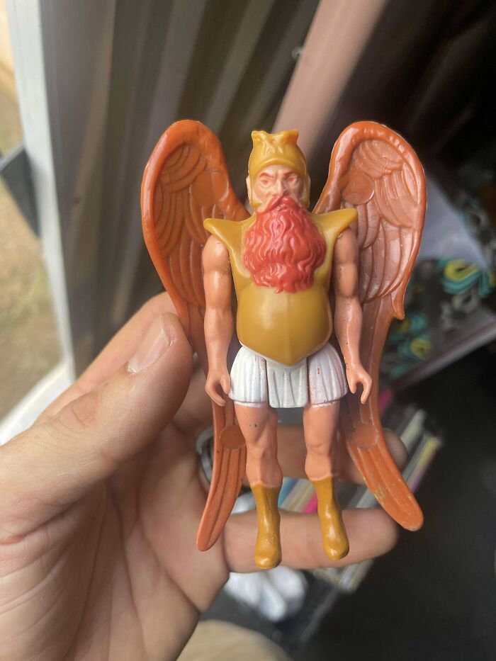 Hand holding a vintage toy figure with wings, reminiscent of childhood memories.