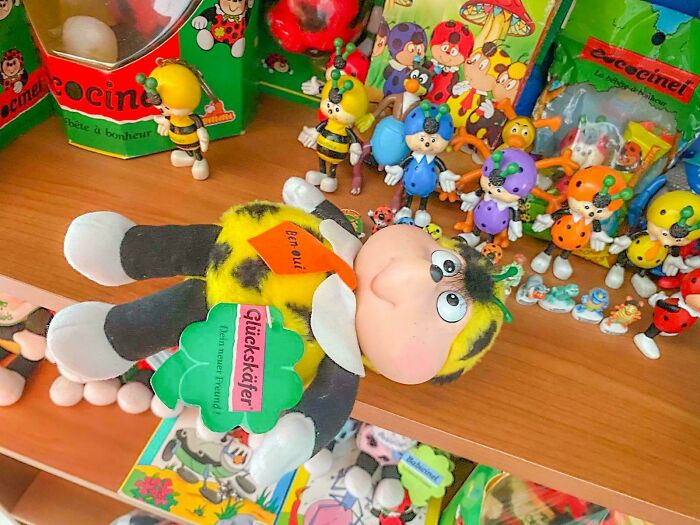 Vintage toys on a shelf, featuring a plush bee character and various colorful figurines, evoking childhood nostalgia.