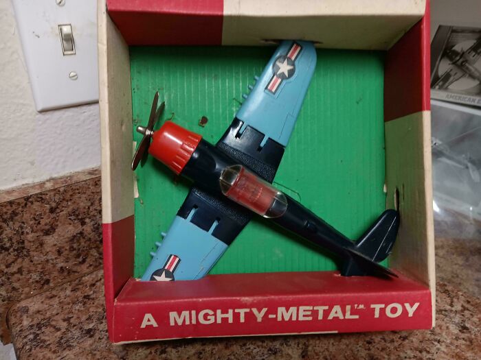 Vintage toy airplane in original packaging labeled “A Mighty-Metal Toy," evokes childhood nostalgia.