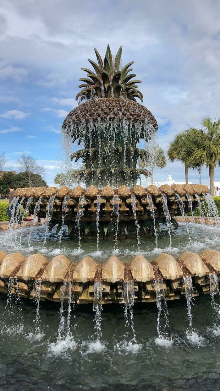 Pineapple fountain with cascading water under a cloudy sky, a unique tourist-interesting experience.