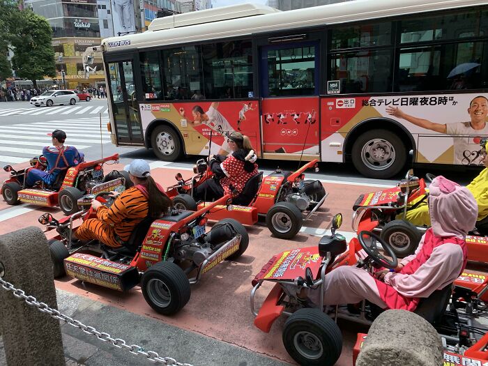People dressed in costumes driving go-karts on a city street, showcasing tourist-interesting experiences.