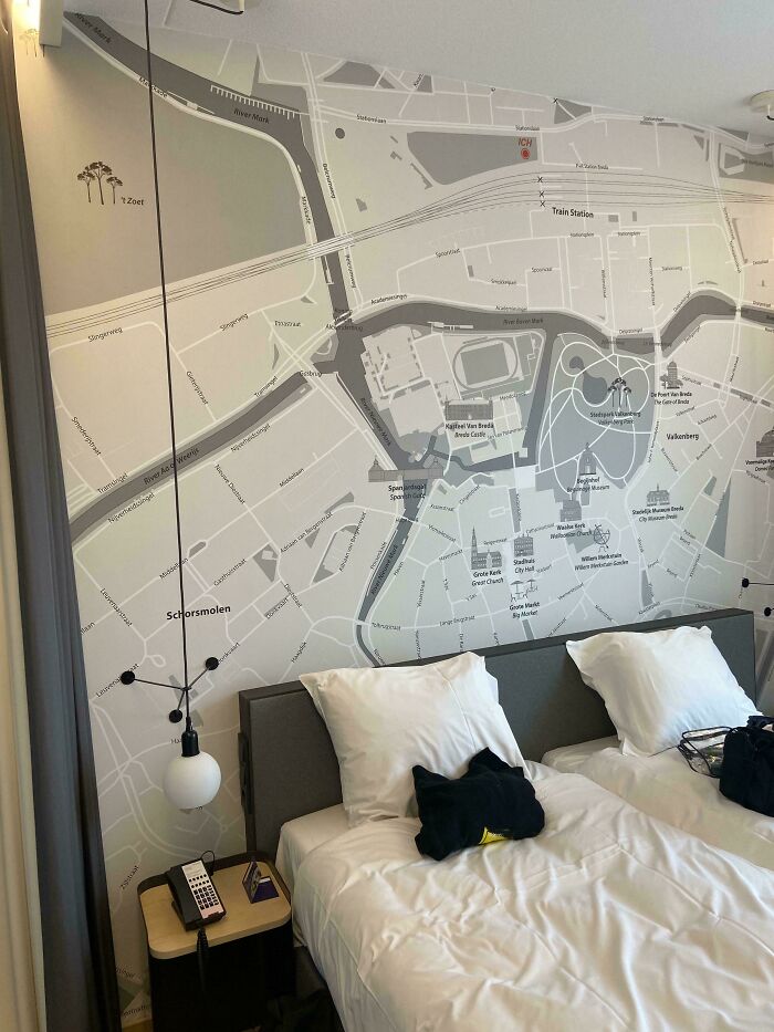 Hotel room with a map decor on the wall behind two beds, offering unique tourist-interesting experiences.