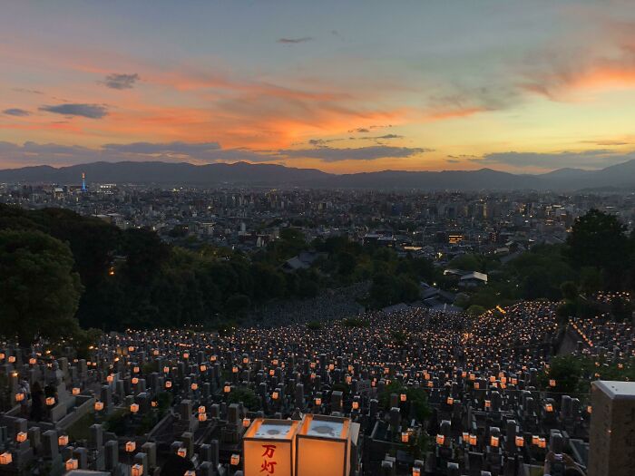 Lanterns lighting up a cemetery at sunset, offering a serene Tourist-Interesting-Experiences view of the cityscape beyond.