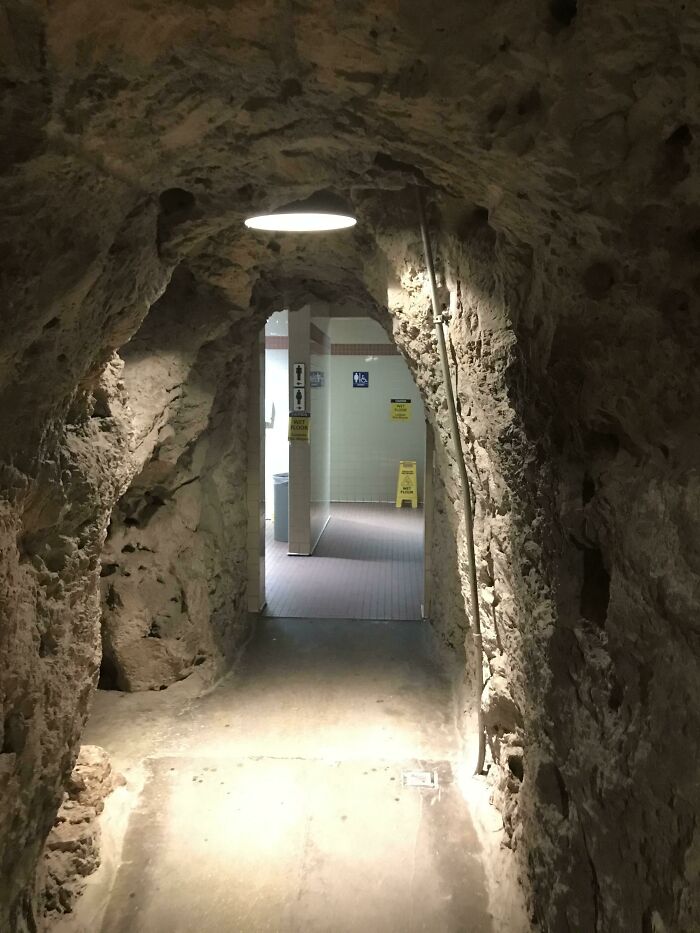 A rocky tunnel leading to a modern interior, offering unique tourist experiences.