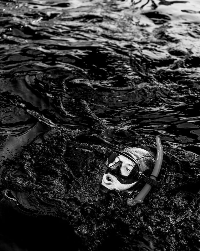 A snorkeler in dark waters, capturing essence of Oslo's streets in black and white.