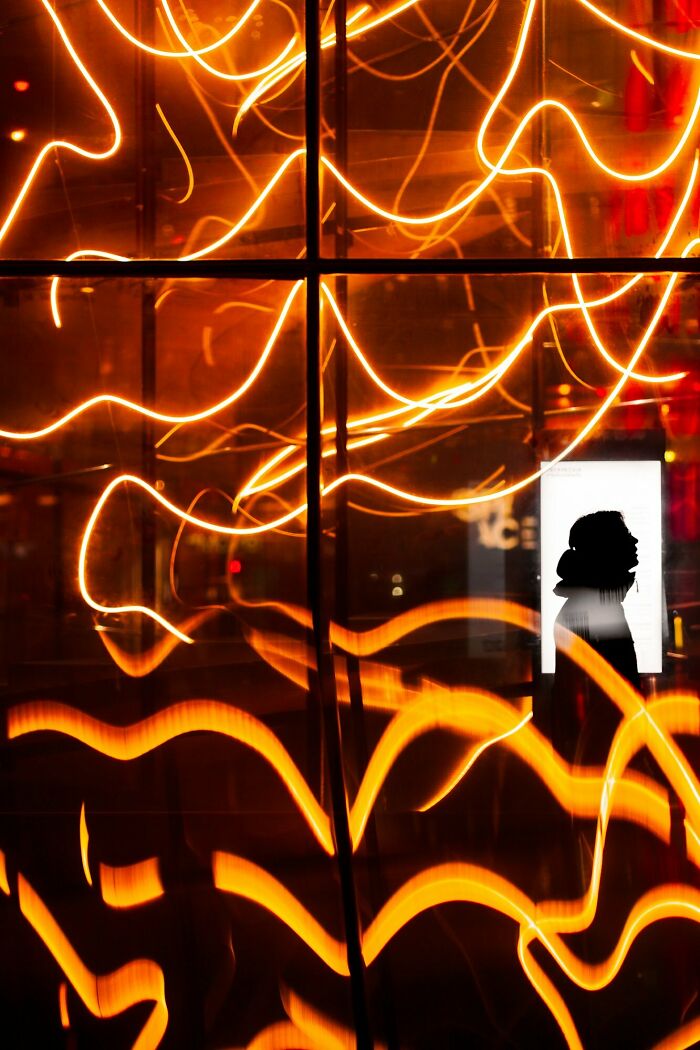 Street photography in Oslo with André's silhouette amidst vibrant orange light trails.