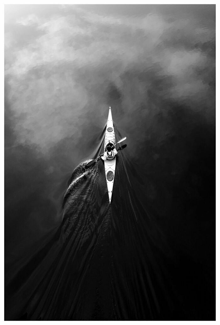 Kayaker paddling on calm waters, capturing Oslo and Stockholm's street essence in black and white.