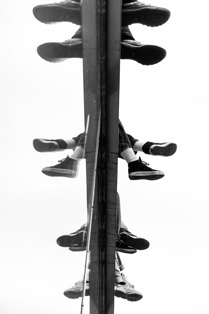 Black and white photo by André capturing mirrored legs of a person sitting in Oslo or Stockholm.