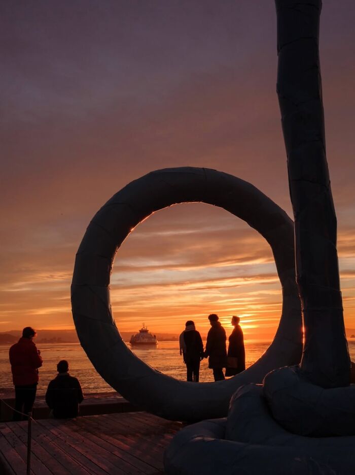 Street art in Oslo at sunset, with silhouettes and a ship on the horizon.