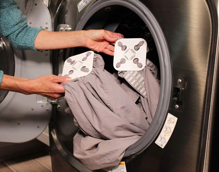 Hands placing clever laundry invention inside a washing machine.