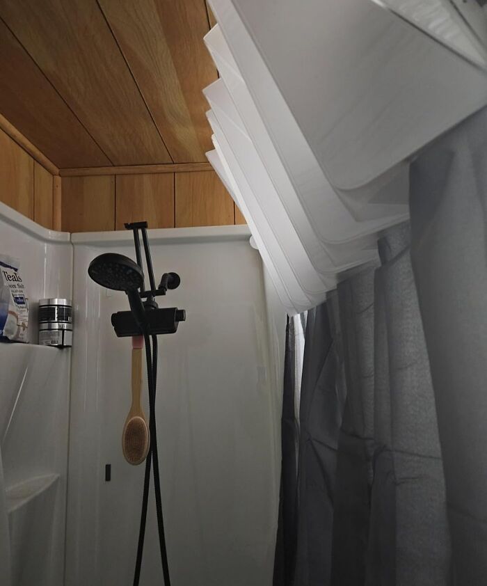 Unique invention of a pleated shower curtain tilted to increase space in a compact shower.