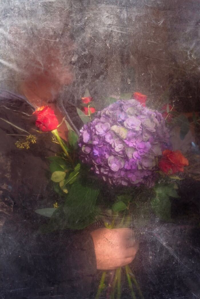 Bouquet of purple and red flowers held by a person in a textured, artistic style, capturing street essence.