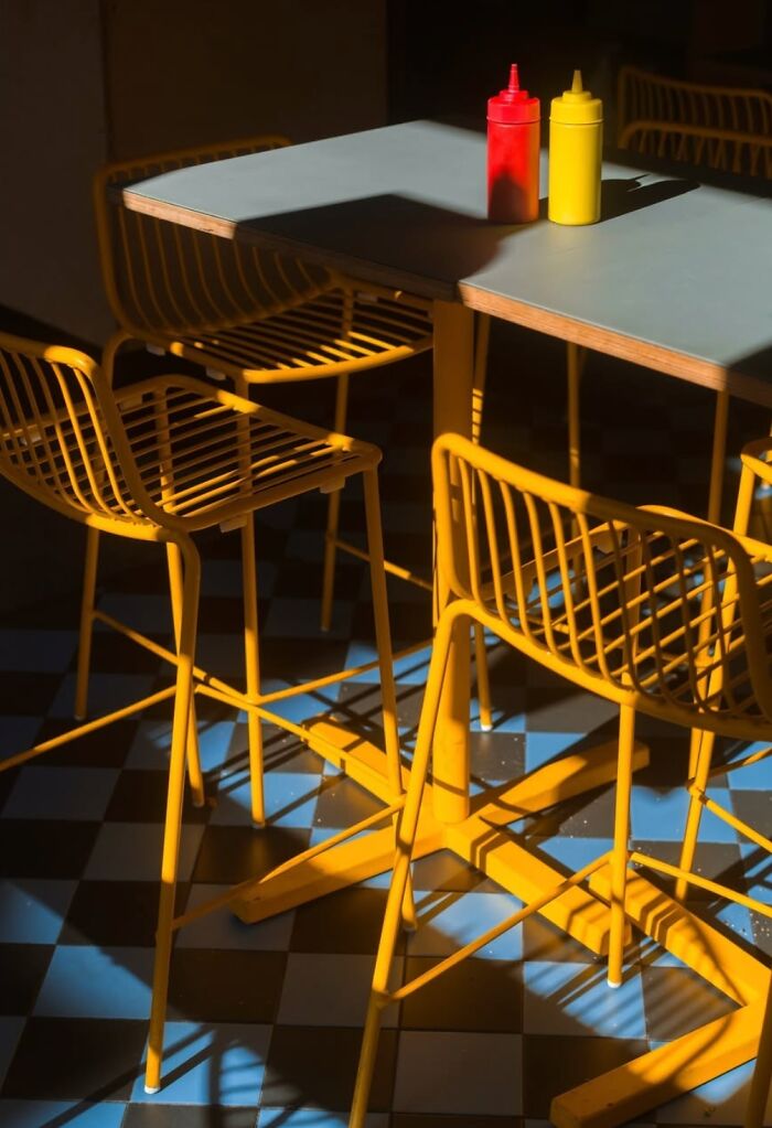 Yellow chairs and table with ketchup and mustard bottles, depicting the streets of Oslo and Stockholm.