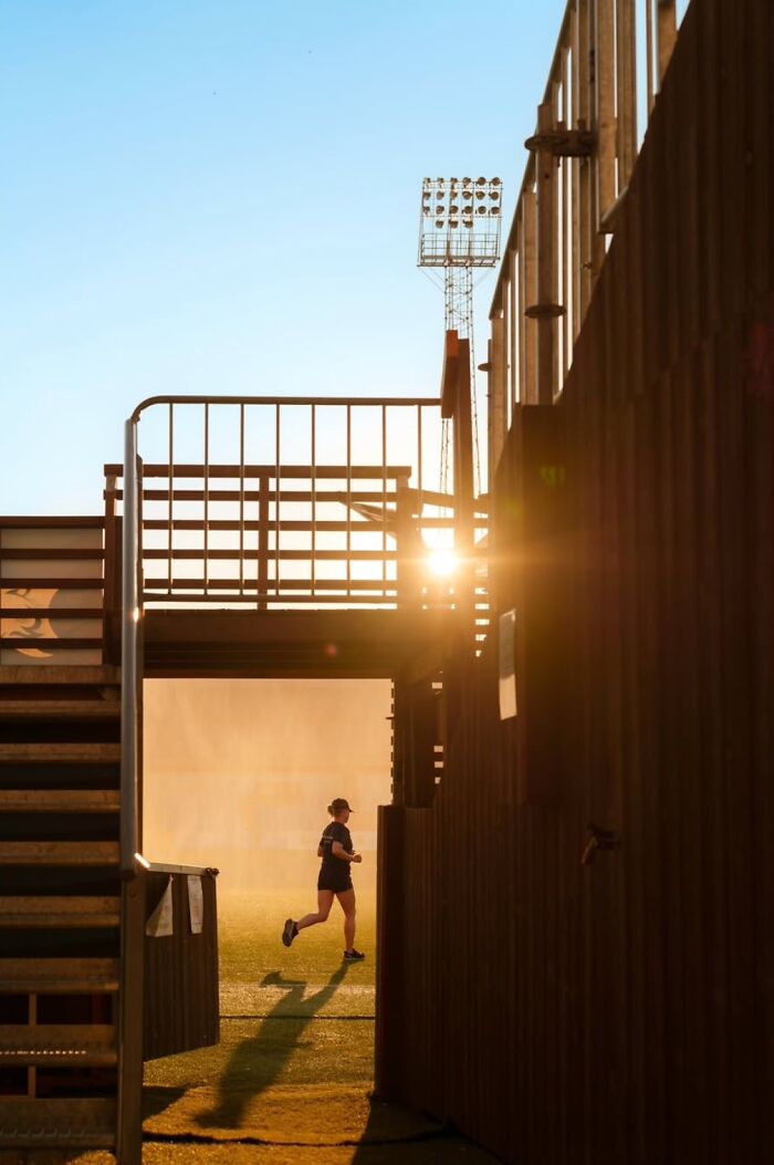 Runner silhouetted by the setting sun in an urban scene, capturing the essence of Oslo's streets.