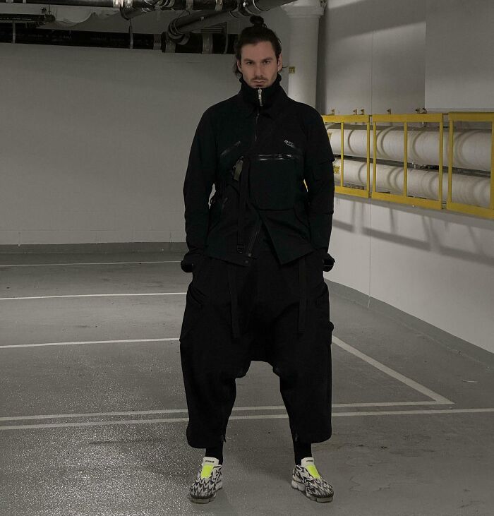 Individual in a bold fashion ensemble, showcasing streetwear style in a parking garage setting.