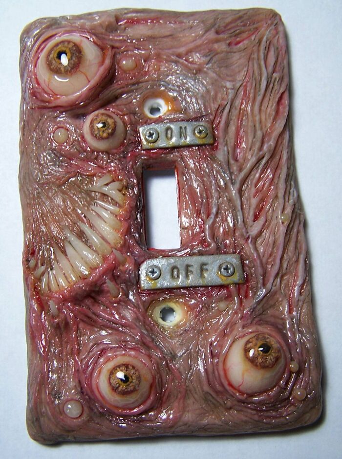 Creepy handmade light switch cover with eye and teeth design.