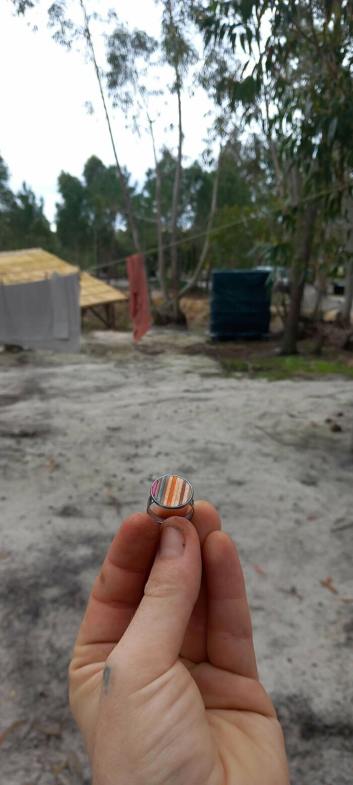 Hand holding a colorful DIY ring with outdoor background.
